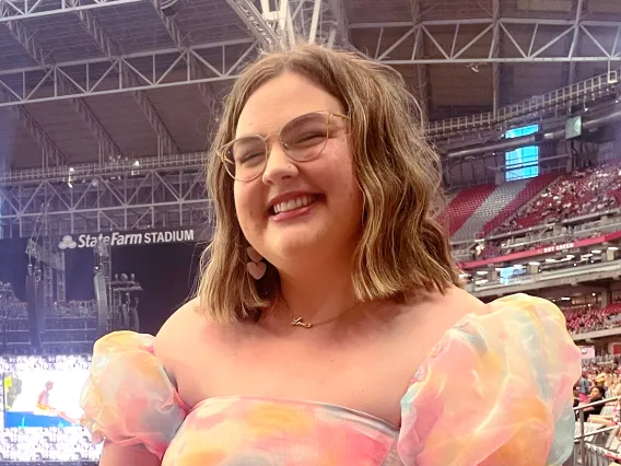 A photo of Lilly at the Eras tour with a poofy, rainbow dress